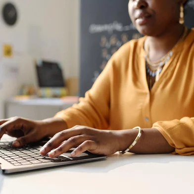 Teacher working on laptop at schoolClose-up of African American teacher working on laptop at schoolFonte: 622274653<!-- NICAID(15648444) -->