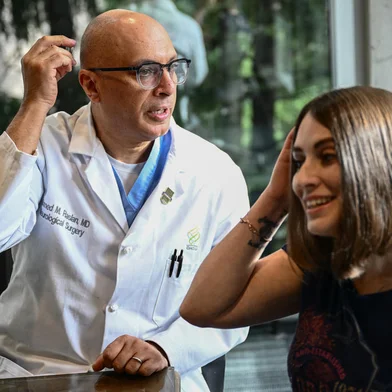 Dr. Ahmed Raslan, professor of neurological surgery talks about the placement of a brain implant with patient Amber Pearson, who received the implant to treat her epilepsy and Obsessive-compulsive disorder (OCD), at the Oregon Health and Science University (OHSU) hospital in Portland, Oregon on January 23, 2024. Amber Pearson used to wash her hands until they bled, terrified by the idea of contamination from everyday items, a debilitating result of her obsessive compulsive disorder. But the repetitive rituals of her condition are largely consigned to memory, thanks to a revolutionary brain implant used to treat epilepsy whose power has now also been turned on OCD for the first time. (Photo by Patrick T. Fallon / AFP)Editoria: HTHLocal: PortlandIndexador: PATRICK T. FALLONSecao: biotechnologyFonte: AFPFotógrafo: STF<!-- NICAID(15669804) -->
