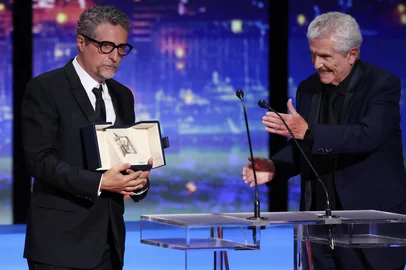 Brazilian director Kleber Mendonca Filho receives the Best Director prize for the film "O Agente Secreto" (The Secret Agent) from French director Claude Lelouch during the closing ceremony at the 78th edition of the Cannes Film Festival in Cannes, southern , on May 24, 2025. (Photo by Sameer AL-DOUMY / AFP)<!-- NICAID(16045267) -->