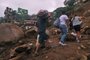 People hold donations as they pass by the zone of a giant landslide at Caxambu neighborhood in Petropolis, Brazil, on February 19, 2022. - A total of 136 bodies have been retrieved to date, according to civil defense officials, in the normally scenic tourist town some 60 kilometers (37 miles) north of Rio de Janeiro. (Photo by MAURO PIMENTEL / AFP)<!-- NICAID(15021845) -->