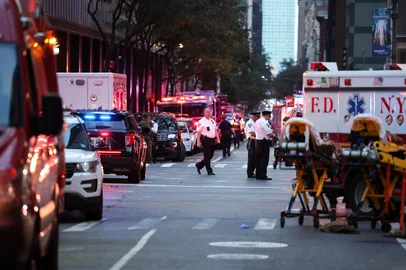 Police are seen near emergency vehicles as they respond to a shooting incident in the Midtown Manhattan neighborhood of New York on July 28, 2025. Police swarmed Midtown Manhattan on Monday as the mayor of New York City said there was "an active shooter investigation" amid reports a police officer had been struck. New York City police commissioner Jessica Tisch said that the gunman, who had been on the loose in the busy Midtown district of Manhattan, had been "neutralized." (Photo by CHARLY TRIBALLEAU / AFP)<!-- NICAID(16089692) -->