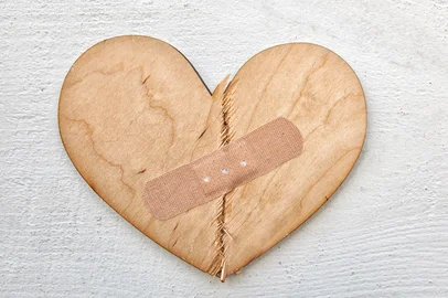 Two parts of broken wooden heart taped by a patch. Concept of the forgiveness, renewal of relations and healing Fonte: 316266849<!-- NICAID(15803146) -->