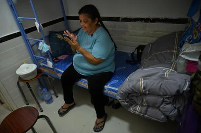 Esta foto tirada em 9 de maio de 2022 mostra a peruana Zoila Lecarnaque Saavedra, recentemente libertada após cumprir pena na prisão por tráfico de drogas e agora aguardando deportação, usando seu telefone em um albergue apertado em Hong Kong. - Zoila Lecarnaque Saavedra selou seu destino quando concordou em transportar um pacote do Peru para Hong Kong - uma decisão que a levou a mais de oito anos de prisão. Um quarto dos prisioneiros de Hong Kong são mulheres, uma porcentagem recorde distorcida por mulas de drogas estrangeiras empobrecidas que muitas vezes são enganadas ou coagidas. (Foto de Peter PARKS / AFP) / PARA ACOMPANHAR A HISTÓRIA DA AFP HONG HONG-CHINA-DROGAS-CRIME,REPORTAGEM ESPECIAL DE MARIA CRISTHIN KUIPER, JEROME TAYLOR E CHRISTIAN SIERRA<!-- NICAID(15160429) -->