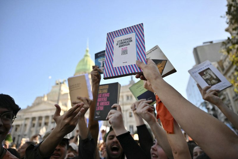Demonstrators raise books during a march in protest of the budget adjustment to public universities in Buenos Aires on April 23, 2024. Tens of thousands of Argentine university students took to the streets Tuesday to protest cuts to higher public education, research and science under budget-slashing new President Javier Milei. (Photo by Luis ROBAYO / AFP)<!-- NICAID(15743601) -->