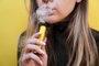 A young girl smokes disposable electronic cigarette. Bright yellow backgroundProibição dos cigarros eletrônicos deve ser mantida no Brasil - Foto: brillianata/stock.adobe.comFonte: 422942092<!-- NICAID(15621053) -->