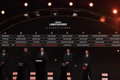 Conmebol's director of competitions and operations Frederico Nantes (C) and ex-footballers Mauro Silva (L) of Brazil, Diego Lugano (2-L) of Uruguay, Ricardo Tavarelli (2-R) of Paraguay and Maximiliano Rodriguez of Argentina, stand under the screen displaying the conformation of the groups for the group phase of the Libertadores Cup football tournament, during the draw at Conmebol's headquarters in Luque, Paraguay, on March 27, 2023. (Photo by NORBERTO DUARTE / AFP)<!-- NICAID(15387124) -->