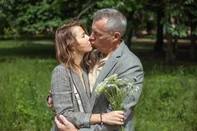 Romantic couple of two mature gray haired man and woman holding bouquet of flowers kissing and falling in love in parkRomantic couple of two mature gray haired man and woman holding bouquet of flowers kissing and falling in love in green natural park outdoors. Happy marriage, loving close relationship in family. Fonte: 560976671<!-- NICAID(16252287) -->