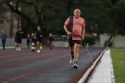 PORTO ALEGRE, RS, BRASIL, 13-05-2026: Ciclo de treinamento para uma maratona: Corredores deficientes visuais,  corredor-guia e treinador comentam sobre a rotina de treinos, a adaptação para as provas e o sentimento envolvido na aventura dos quilômetros. O Projeto Sexto Sentido, há nove anos reúne dezenas de entusiastas da corrida, aliando e conectando pessoas com deficiais visuais de diferentes níveis na prática do esporte. Oneide de Souza Figueiredo, 62 anos, em um dos seus treinos na pista do CETE. A estrutura da pista permite que Oneide faça seus treinos sozinho, usando a guia como condutora de seu trajeto. Foto: Renan Mattos / Agência RBS<!-- NICAID(16285360) -->