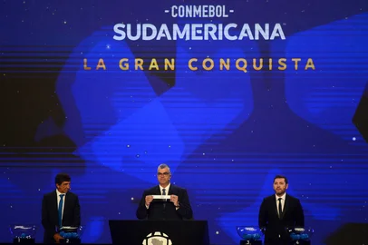 Conmebol's Director of Clubs Competitions, Frederico Nantes (C), shows the slip of Argentina's Lanus next to Racing's head coach Gustavo Costas (L) and Chilean footballer Jose Rojas during the draw for the group stage of the Copa Sudamericana at Conmebol's headquarters in Luque, Paraguay, on March 17, 2025. (Photo by DANIEL DUARTE / AFP)<!-- NICAID(15997695) -->