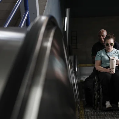 PORTO ALEGRE, RS, BRASIL, 05-01-2025: Desde a enchente que as escadas rolantes e o elevador da estação mercado estão fora de operação. Pessoas com mobilidade restrita ou cadeirantes, por exemplo, precisam ser carregadas no colo pelos seguranças da trensurb para acessar o local. a imagem, Aline Barbosa, de Canoas, é acompanhada pelo segurança. O novo elevador está sendo implementado no espaço. Fotos: Duda Fortes/Agencia RBS<!-- NICAID(16198323) -->