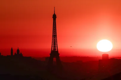 The sun rises by the Eiffel Tower and the Sacre Coeur Basilica ontop of the Montmartre hill in Paris on July 1, 2025, as the city is on red alert for high temperatures, with the top of the Eiffel Tower shut, polluting traffic banned and speed restrictions in place as a searing heatwave gripped Europe. Scientists say human-induced climate change is making such heatwave events more intense, frequent and widespread. Temperatures in France were expected to hit a peak today, according to the Meteo France weather agency, with the highest extreme heat warning in place in 16 departments across the country. (Photo by Thibaud MORITZ / AFP)Editoria: WEALocal: ParisIndexador: THIBAUD MORITZSecao: global changeFonte: AFPFotógrafo: STF<!-- NICAID(16073682) -->