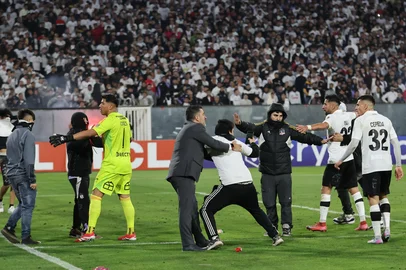 Players of Colo Colo calm fans on the pitch during the Copa Libertadores group stage football match between Chile's Colo Colo and Brazil's Fortaleza at the Monumental David Arellano stadium in Santiago, on April 10, 2025. Two people were killed Thursday in a stampede as a group of fans tried to force their way into Colo Colo's Monumental stadium in Santiago to watch the match against Brazil's Fortaleza for the Copa Libertadores 2025, authorities said. (Photo by Javier TORRES / AFP)<!-- NICAID(16014857) -->