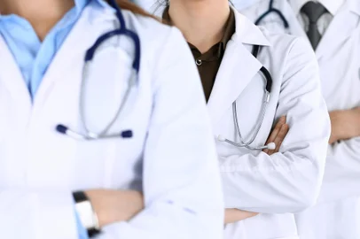 Group of modern doctors standing as a team with arms crossed in hospital office. Physicians ready to examine and help patients. Medical help, insurance in health care, best desease treatment and medicine conceptMédicos. Foto: Iryna / stock.adobe.comFonte: 296904883<!-- NICAID(15728330) -->