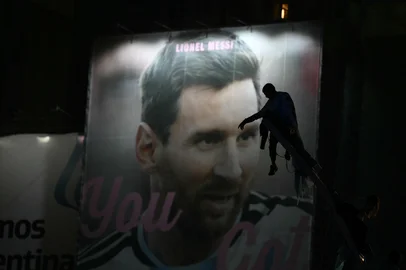 Argentina's fans are silhouetted as they stand atop a pole in front of an image of Lionel Messi near the Obelisk after Argentina lost the FIFA World Cup final football match against Spain in Buenos Aires on July 19, 2026. Spain won by 1-0. (Photo by Luis ROBAYO / AFP)<!-- NICAID(16330918) -->