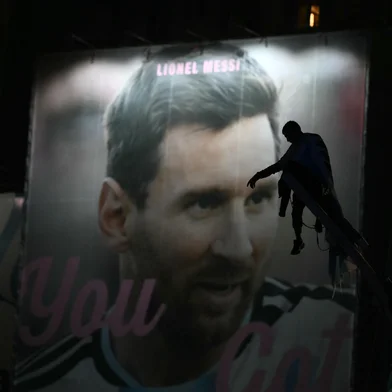 Argentina's fans are silhouetted as they stand atop a pole in front of an image of Lionel Messi near the Obelisk after Argentina lost the FIFA World Cup final football match against Spain in Buenos Aires on July 19, 2026. Spain won by 1-0. (Photo by Luis ROBAYO / AFP)<!-- NICAID(16330918) -->