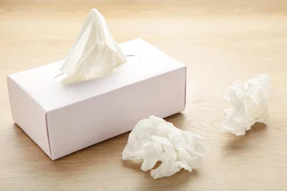 Box with paper tissues and used crumpled napkins on light backgroundLenços de papel. Top view. Foto: Mouse family / stock.adobe.comFonte: 373851537<!-- NICAID(15459933) -->