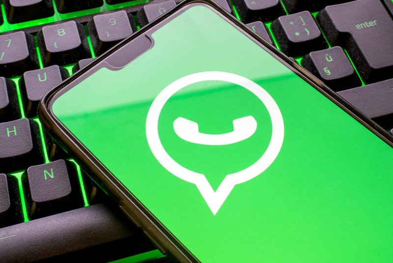 Mobile phone with green whatsapp logo on display and colorful illuminated keyboard close up. Smartphone concept using the messaging application with the symbol on screenFonte: 412314109<!-- NICAID(15140084) -->
