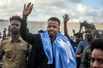 HASSAN ALI ELMI / AFP Somali international referee Omar Abdulkadir Artan waves to supporters while draped in the Somali flag as he is welcomed ahead of a solidarity football match after returning to Somalia in Mogadishu on June 10, 2026. Somali referee Omar Artan, who was denied entry to the United States for the World Cup, returned to a hero's welcome in Mogadishu and vowed to take part in the next tournament in 2030. Artan's rejection has sparked outrage at home.Artan, who in 2025 was named men's referee of the year by the Confederation of African Football (CAF), was barred from entering the US on Saturday after arriving at Miami International Airport. (Photo by Hassan Ali Elmi / AFP)<!-- NICAID(16303549) -->