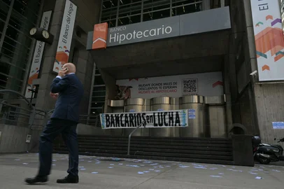 A man walks past the Hipotecario bank displaying a union banner during a 24-hour strike called by workers' unions against the economic policies of President Javier Milei in Buenos Aires on April 10, 2025. The 24-hour general strike started at midnight as President Javier Milei awaits news on a fresh IMF loan.