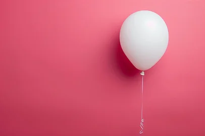 Balão branco voando em um fundo rosa. <!-- NICAID(15840150) -->