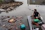 An animal rescue volunteer, moves among floating debris on a boat in floodwaters at Kherson on June 8, 2023, after the city was engulfed by rising water levels following damage sustained at Kakhovka hydroelectric power plant dam. Ukrainian President Volodymyr Zelensky has visited the region flooded by the breached Kakhovka dam, as the regional governor said 600 square kilometres were underwater. (Photo by ALEKSEY FILIPPOV / AFP)<!-- NICAID(15451384) -->