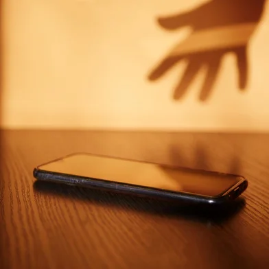 Fear of missing out visualization. Shadow hand taking smartphone. Social media dependence. FOMO anxietyFonte: 419358293<!-- NICAID(15472463) -->