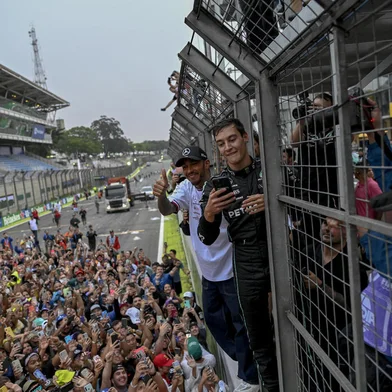 Mercedes' British driver George Russell (R) and Lewis Hamilton (L) celebrate with fans after the Formula One Brazil Grand Prix at the Autodromo Jose Carlos Pace racetrack, also known as Interlagos, in Sao Paulo, Brazil, on November 13, 2022. (Photo by MAURO PIMENTEL / AFP)<!-- NICAID(15264147) -->