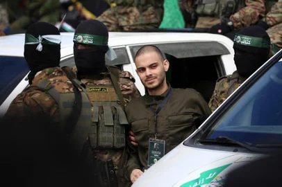 Hamas fighters accompany Israeli hostage Omer Wenker to be handed over to the Red Cross in Nuseirat in the central Gaza Strip, after his release as part of the seventh hostage-prisoner exchange on February 22, 2025. Three more Israeli hostages were freed by Hamas militants at a ceremony in central Gaza on February 22 after two others were released in the southern part of the Palestinian territory. (Photo by Eyad BABA / AFP)<!-- NICAID(15981814) -->