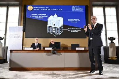Academy of Sciences permanent secretary Jan Teorell, of the Nobel assembly delivers a press conference in front of a screen showing results of the research of laureates of the 2024 Sveriges Riksbank Prize in Economic Sciences in Memory of Alfred Nobel, Daron Acemoglu, Simon Johnson and James A Robinson during the announcement by the Royal Swedish Academy of Sciences in Stockholm, Sweden on October 14, 2024. The Nobel prize in economics was awarded on October 14, 2024, to Turkish-American Daron Acemoglu and British-Americans Simon Johnson and James Robinson for research into wealth inequality between nations. The trio was honoured "for studies of how institutions are formed and affect prosperity", the jury said. (Photo by Christine Olsson/TT / TT NEWS AGENCY / AFP) / Sweden OUTEditoria: HUMLocal: StockholmIndexador: CHRISTINE OLSSON/TTSecao: economy (general)Fonte: TT NEWS AGENCYFotógrafo: STR<!-- NICAID(15889883) -->