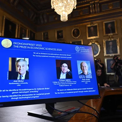 A screen displays the portraits of the 2025 prize winners (L-R) Joel Mokyr, Philippe Aghion and Peter Howitt, during the announcement of the winners of the 2025 Nobel Prize in Economics, the Sveriges Riksbank Prize in Economic Sciences in Memory of Alfred Nobel, at the Royal Swedish Academy of Sciences in Stockholm, Sweden, on October 13, 2025. The Nobel prize in economics was awarded to American-Israeli Joel Mokyr, France's Philippe Aghion and Canada's Peter Howitt for work on technology's impact on sustained economic growth. (Photo by Anders WIKLUND / TT NEWS AGENCY / AFP) / Sweden OUT / SWEDEN OUT / SWEDEN OUT<!-- NICAID(16145225) -->