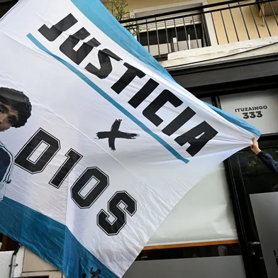 A fan holds a flag with his image of late Diego Maradona in front of the San Isidro court ahead of the trial for the death of late Argentine football legend Diego Maradona in San Isidro, Buenos Aires province, Argentina on March 11, 2025. Four years after Diego Maradona's death, the trial of seven health professionals begins this Tuesday in Argentina to determine their responsibilities in the death of the soccer legend. (Photo by Luis ROBAYO / AFP)<!-- NICAID(15993071) -->