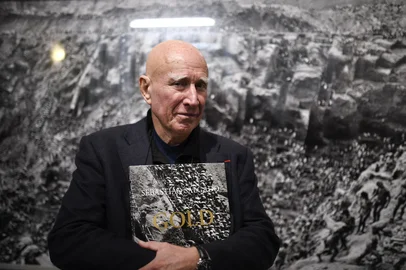 Brazilian photographer Sebastiao Salgado stands in front of his work with his book at the Bene Taschen gallery at his exhibition Gold in Cologne on February 6, 2020. (Photo by INA FASSBENDER / AFP) / RESTRICTED TO EDITORIAL USE - MANDATORY MENTION OF THE ARTIST UPON PUBLICATION - TO ILLUSTRATE THE EVENT AS SPECIFIED IN THE CAPTIONEditoria: ACELocal: CologneIndexador: INA FASSBENDERSecao: photographyFonte: AFPFotógrafo: STR<!-- NICAID(16044202) -->