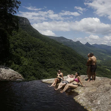 TRÊS FORQUILHAS, RS, BRASIL, 25-01-2026: A técnica em segurança do trabalho, Jaqueline Maciel (C, de rosa), 34 anos, com grupo de amigos de Osório na piscina natural com borda infinita no topo da Cascata da Pedra Branca, em Três Forquilhas, no Litoral Norte. O acesso é feito por um caminho íngreme por dentro da mata, com desnível de aproximadamente 400 metros e pouco mais de um quilômetro de extensão. Foto: Mateus Bruxel/Agência RBSIndexador: MATEUS BRUXEL<!-- NICAID(16214929) -->