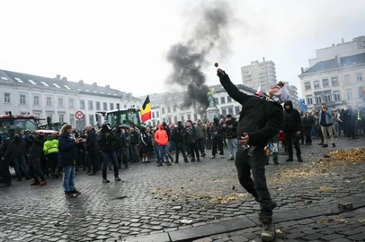 Um agricultor atira uma batata perto do Parlamento Europeu, durante um protesto de agricultores para denunciar as reformas da Política Agrícola Comum (PAC) e acordos comerciais como o Mercosul, em Bruxelas, em 18 de dezembro de 2025, organizado pela Copa-Cogeca, a principal associação que representa agricultores e cooperativas agrícolas na UE.Os agricultores da UE, particularmente na França, temem que o acordo com o Mercosul - que será discutido na reunião de líderes da UE - os prejudique devido ao fluxo de produtos mais baratos do gigante agrícola Brasil e seus vizinhos. Eles também se opõem aos planos apresentados pela Comissão Europeia para reformular os enormes subsídios agrícolas do bloco de 27 nações, temendo que menos dinheiro chegue até eles.<!-- NICAID(16189630) -->