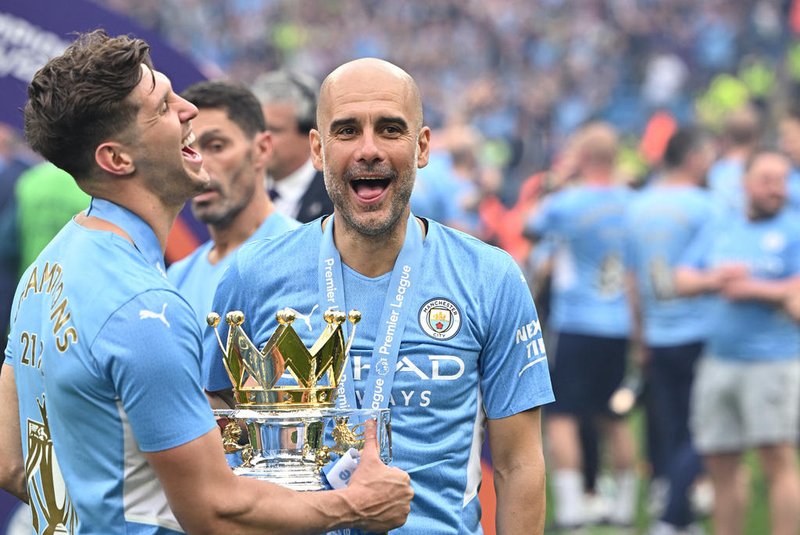Manchester City's Spanish manager Pep Guardiola (R) and Manchester City's English defender John Stones (L) celebrate with the Premier League trophy on the pitch after the English Premier League football match between Manchester City and Aston Villa at the Etihad Stadium in Manchester, north west England, on May 22, 2022. - Manchester City won the Premier League for the fourth time in five seasons after a pulsating title race reached a dramatic conclusion as the champions staged an incredible comeback from two goals down to beat Aston Villa 3-2 on Sunday. (Photo by Oli SCARFF / AFP) / RESTRICTED TO EDITORIAL USE. No use with unauthorized audio, video, data, fixture lists, club/league logos or 'live' services. Online in-match use limited to 120 images. An additional 40 images may be used in extra time. No video emulation. Social media in-match use limited to 120 images. An additional 40 images may be used in extra time. No use in betting publications, games or single club/league/player publications. / Editoria: SPOLocal: ManchesterIndexador: OLI SCARFFSecao: soccerFonte: AFPFotógrafo: STR<!-- NICAID(15103474) -->