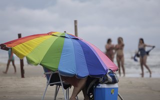 TORRES, RS, BRASIL, 18-01-2026: Apesar da chuva e do céu encoberto, veranistas permanecem na Praia Grande, em Torres. Guarda-sol virou abrigo da chuva e do vento em alguns períodos do domingo. Foto: Mateus Bruxel/Agência RBSIndexador: MATEUS BRUXEL<!-- NICAID(16206235) -->