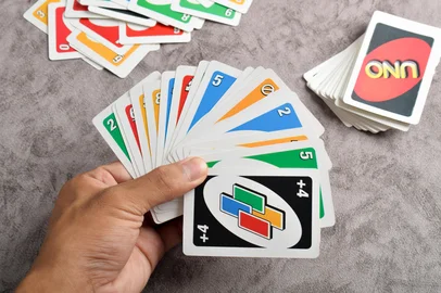 Pasuruan, Indonesia - November 26, 2024: Man playing Uno card game. Close up of hands holding card fan<!-- NICAID(16005404) -->