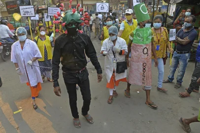 A man from a Non-governmental organization (NGO) wearing an outfit resembling the Covid-19 coronavirus moves around a marketplace urging people to follow the safety protocols during an awareness drive held in Siliguri on April 25, 2021. (Photo by DIPTENDU DUTTA / AFP)<!-- NICAID(14766149) -->