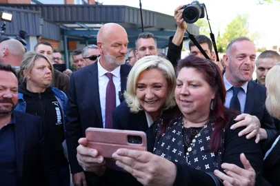 French far-right party Rassemblement National (RN) presidential candidate Marine Le Pen (C), flanked by RN member of parliament Bruno Bilde (L) and Henin-Beaumont's RN mayor Steeve Briois (R), is photographed with a mobile phone by a supporter as she leaves the polling station during the second round of France's presidential election in Henin-Beaumont, northern France, on April 24, 2022. - The French began voting on April 24, 2022 to elect their next president and choose, as in 2017, between France's President and La Republique en Marche (LREM) candidate for re-election Emmanuel Macron and France's far-right party Rassemblement National's (RN) presidential candidate Marine Le Pen. (Photo by Thomas SAMSON / AFP)<!-- NICAID(15076459) -->