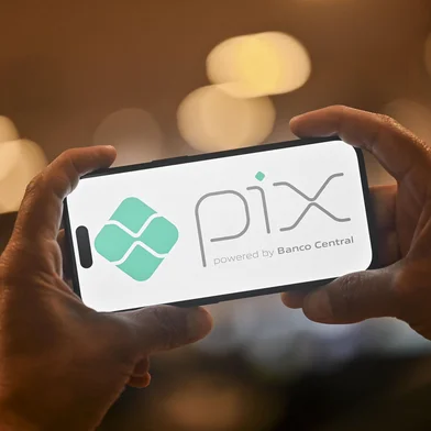 This photo illustration shows a man holding a smartphone displaying the logo of Pix, Brazil's free instant payment system developed by the Central Bank, which has surged in popularity, in Rio de Janeiro, Brazil on July 31, 2025. (Photo by MAURO PIMENTEL / AFP)Editoria: FINLocal: Rio de JaneiroIndexador: MAURO PIMENTELSecao: financial and business serviceFonte: AFPFotógrafo: STF<!-- NICAID(16092219) -->