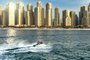 man bashing the waves on the sea with dubay skyline in the backgroundFonte: 296154954<!-- NICAID(14820203) -->