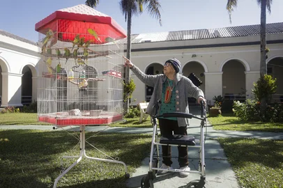 PORTO ALEGRE, RS, BRASIL, 21-07-2025: Marlene Garcia Barreto, 100 anos, com o passarinhos no jardim da ala feminina do Asilo Padre Cacique. Ela é a moradora com mais idade na instituição. O Asilo Padre Cacique é uma instituição filantrópica de longa permanência para idosos que há 126 anos acolhe pessoas idosas em vulnerabilidade social e econômica. Foto: Mateus Bruxel/Agência RBSIndexador: MATEUS BRUXEL<!-- NICAID(16084696) -->