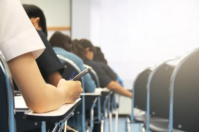 Hands university student holding pen writing /calculator doing examination / study or quiz, test from teacher or in large lecture room, students in uniform attending exam classroom educational school.Fonte: 312397076<!-- NICAID(14793488) -->