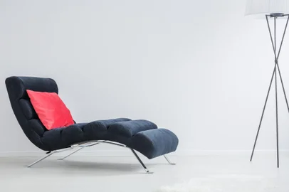 Pink cushion placed on psychologist's navy blue couch in white office<!-- NICAID(15909571) -->
