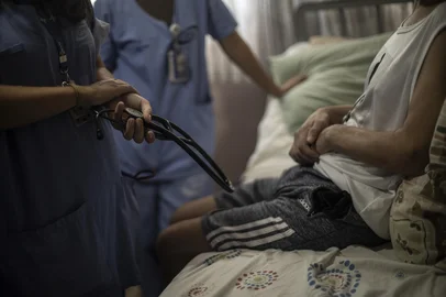 André Ávila / Agencia RBS PORTO ALEGRE, RS, BRASIL, 12-03-2026: Reportagem de GZH acompanhou um turno de trabalho dos profissionais de saúde do Hospital Conceição, que fazem parte do Programa de Atenção Domiciliar. Pacientes que podem receber alta do hospital mas que ainda precisam de acompanhamento médico, recebem as equipes pelo menos uma vez por semana em suas casas. Pacientes com AVC, dificuldade de locomoção, com câncer ou alguma doença terminal estão na lista do programa que já serviu de referência para a criação do Programa Melhor em Casa, do Governo Federal. Na foto: Equipe na casa de Natália Schmik, esposa de Geraldo Borba Melo, paciente do PAD (Foto: André Ávila/Agência RBS)Indexador: Andre Avila<!-- NICAID(16245047) -->