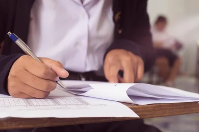 arrowsmith2 / adobe.stock.com Close up to students writing and reading exam answer sheets exercises in classroom of school with stress.16:9 styleFonte: 198517049<!-- NICAID(16363775) -->
