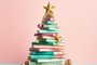 On a crisp winter morning, a festive stack of books with a golden star on top stands proudly against a vibrant pastel christmas tree, bringing a sense of joy and hope for the new yearFonte: 647176919<!-- NICAID(15623267) -->