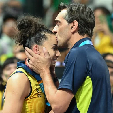 Brazil's #10 Gabriela Braga Guimaraes (L) receives a kiss after the women's preliminary round volleyball match between Brazil and Poland during the Paris 2024 Olympic Games at the South Paris Arena 1 in Paris on August 4, 2024. Brazil won the match 3-0. (Photo by Natalia KOLESNIKOVA / AFP)<!-- NICAID(15832565) -->