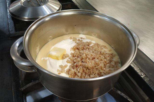 Misture o leite condensado, a manteiga, o creme de leite e mais da do metade do pinhão picado em uma panela.<!-- NICAID(15133653) -->