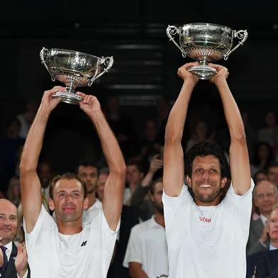 Poland's Lukasz Kubot (L) and Brazil's Marcelo Melo (R) hold up their winners' trophies during the presentation after beating Austria's Oliver Marach and Croatia's Mate Pavic during their men's doubles final match on the twelfth day of the 2017 Wimbledon Championships at The All England Lawn Tennis Club in Wimbledon, southwest London, on July 15, 2017. / AFP PHOTO / Glyn KIRK / RESTRICTED TO EDITORIAL USE